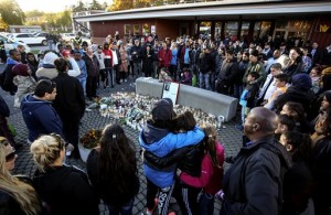 People stand outside Kronan school after  yesterday's attack, in Trollhattan, Sweden, Friday, Oct. 23, 2015. It was a racially motivated, carefully planned rampage, police say. The 21-year-old masked man marched through a Swedish school with a sword and a knife, methodically selecting his victims. Within minutes, two people had been stabbed to death and two others seriously wounded before the attacker was fatally shot by police. (Bjorn Larsson Rosvall/TT News Agency via AP)  SWEDEN OUT