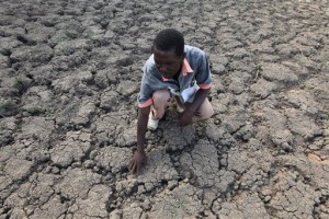 In this photo taken Sunday Jan. 29, 2016, Last Zimaniwa feels the broken ground at a spot which is usually a reliable water source that has dried up due to lack of rains in the village of Chivi , Zimbabwe. Zimbabwean president Robert Mugabe has declared a state of disaster as the country struggles to deal with a drought afflicting the region. (AP Photo/Tsvangirayi Mukwazhi)